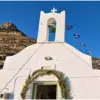 Λευκή πρόσοψη του ναού της Αγίας Μαρίνας Σίφνου, με καμπαναριό και είσοδο στολισμένη με φοινικόφυλλα.