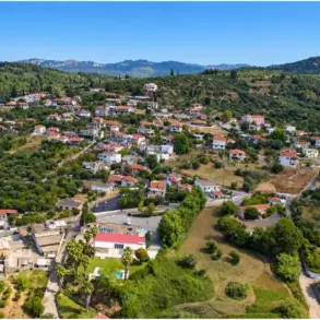Agios Georgios bei Pyrgos aus der Drohnenperspektive, Ziegeldächer zwischen Olivenhainen und niedrigen Hügeln.