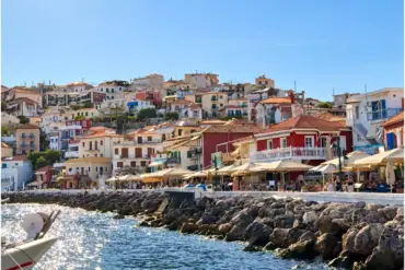 Casas de colores de Parga sobre el paseo marítimo, con las sombrillas de los locales y la escollera que protege la costa.