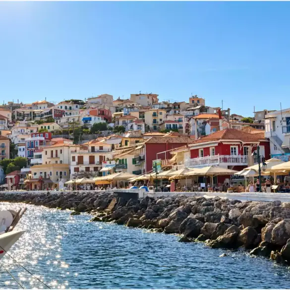 Casas de colores de Parga sobre el paseo marítimo, con las sombrillas de los locales y la escollera que protege la costa.