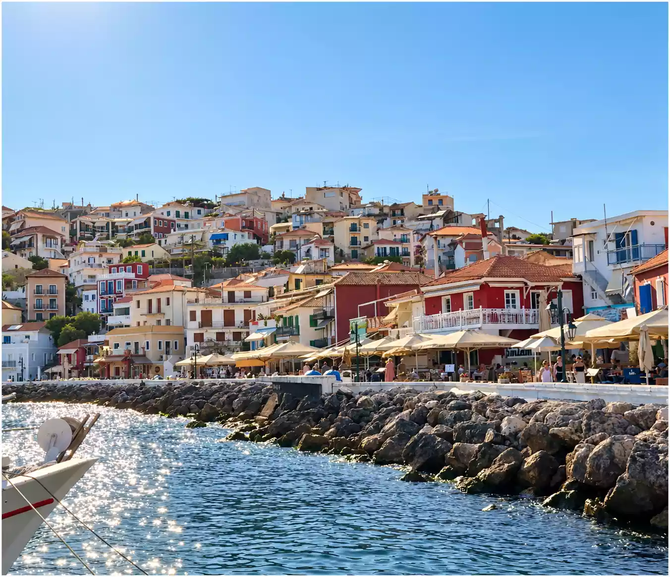 Casas de colores de Parga sobre el paseo marítimo, con las sombrillas de los locales y la escollera que protege la costa.